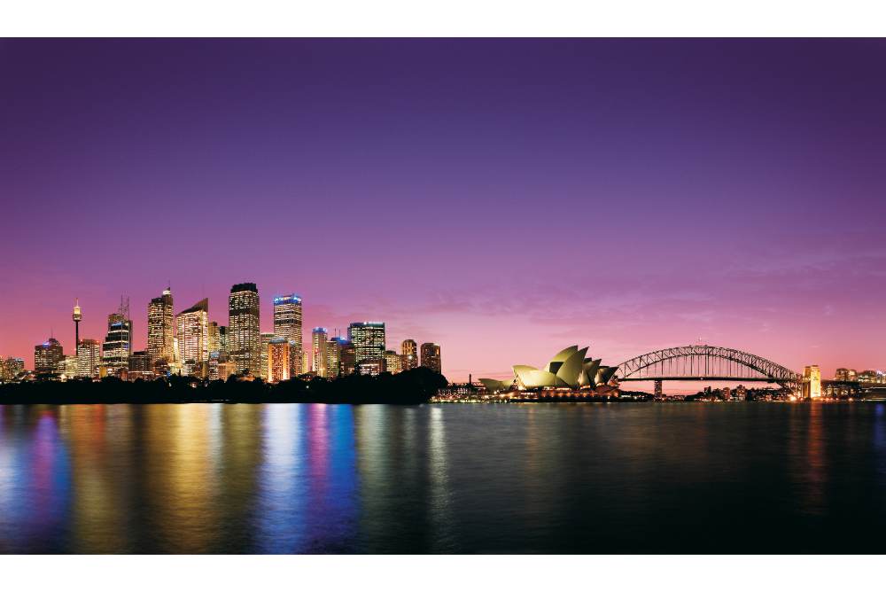 An inspiring picture for people moving to Australia, of Sydney Opera House and skyline at daybreak